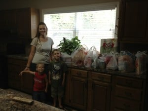 Mom and boys near a pile of donated items in bags.